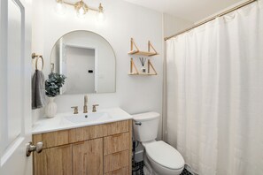 A bathroom with a white sink, wooden vanity, a toilet, and a shower curtain. - Cozy North Austin Getaway  Peaceful  Near Domain (Austin)