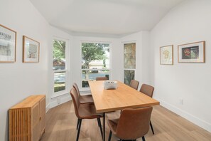 A modern dining room with a wooden table and brown chairs, large windows, and framed artwork on the walls. - Cozy North Austin Getaway  Peaceful  Near Domain (Austin)