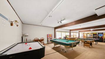 A recreational room with pool tables, foosball tables, and arcade games.