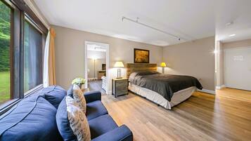 A modern bedroom with a large bed, a sofa, a bedside table, and a lamp.