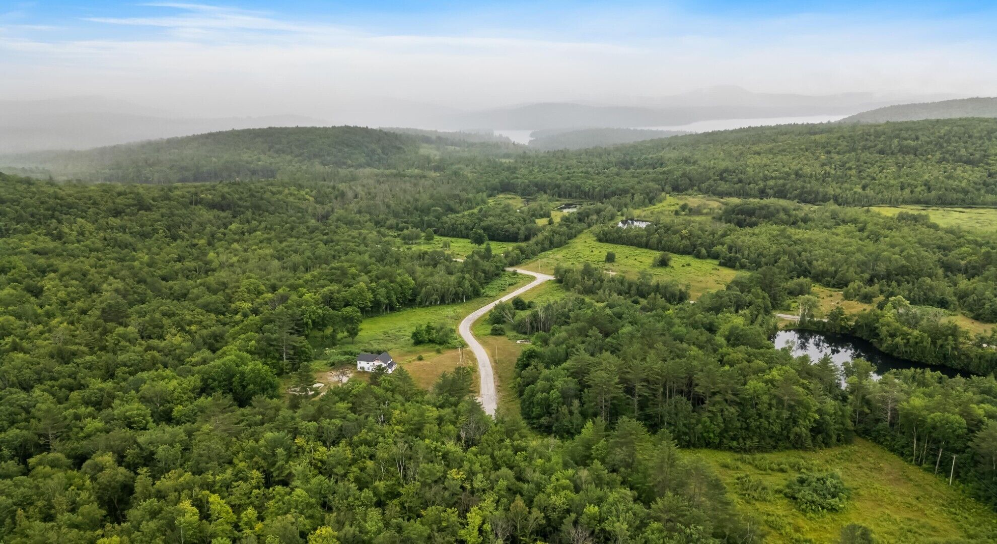 Üppige grüne Landschaft mit einer kurvenreichen Straße und einem kleinen Gebäude.