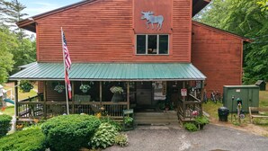A rustic building with a green roof, a moose logo, and a welcoming sign. - Mountain Magic | 2BR Condo w/ Balcony & Fireplace (Stoneham)