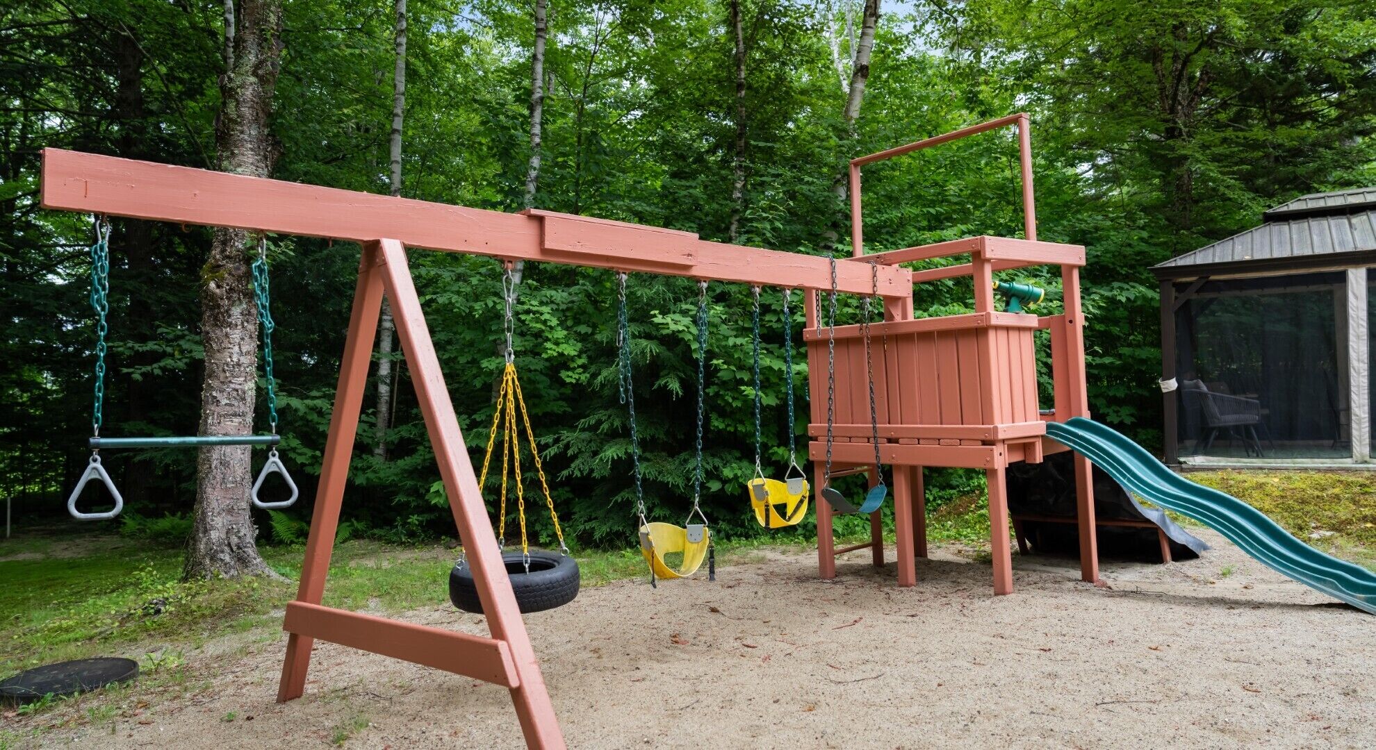 Een speelplaats met schommels, een glijbaan en een klimconstructie.