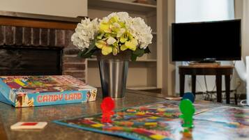 Une table sur laquelle est posé un jeu de société intitulé « Candy Land », un vase avec des fleurs blanches et, au fond, un téléviseur.