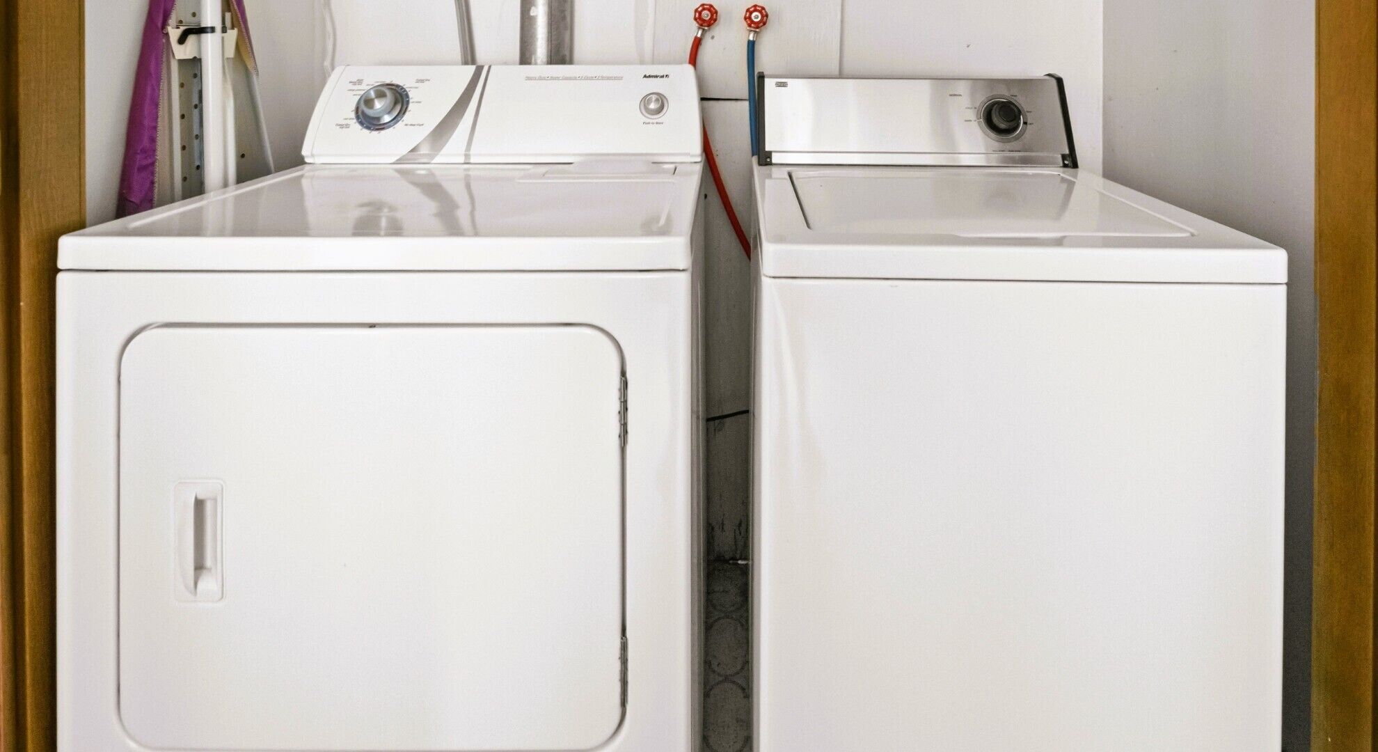 Twee voorladers wasmachines in een wasserij met een houten deurkozijn.