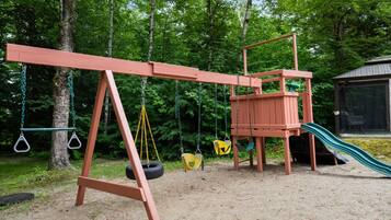 A playground with swings, a slide, and a climbing structure.