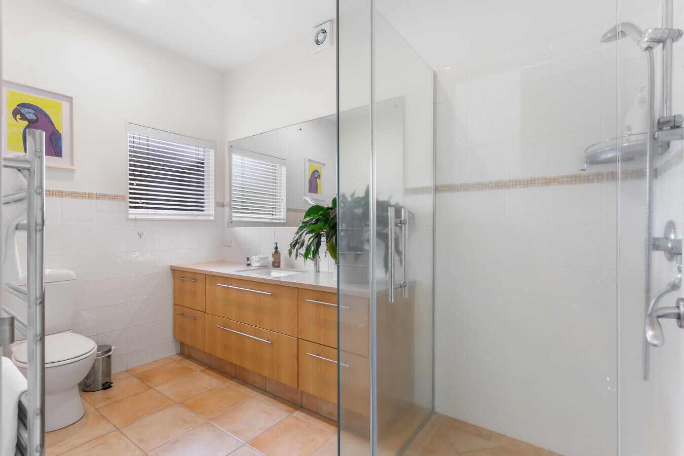Ein modernes Badezimmer mit einer Duschkabine aus Glas, einer weißen Toilette, einem hölzernen Waschtisch mit Waschbecken und einem Spiegel.