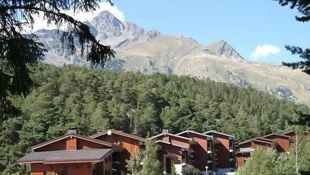 Un rifugio alpino con diverse cabine in legno, un'area di parcheggio e vista sulle montagne circostanti.