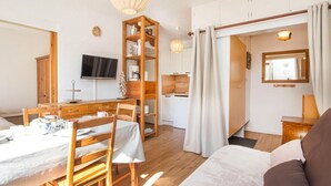 Un accogliente soggiorno con un tavolo da pranzo in legno, un divano e una TV a parete.