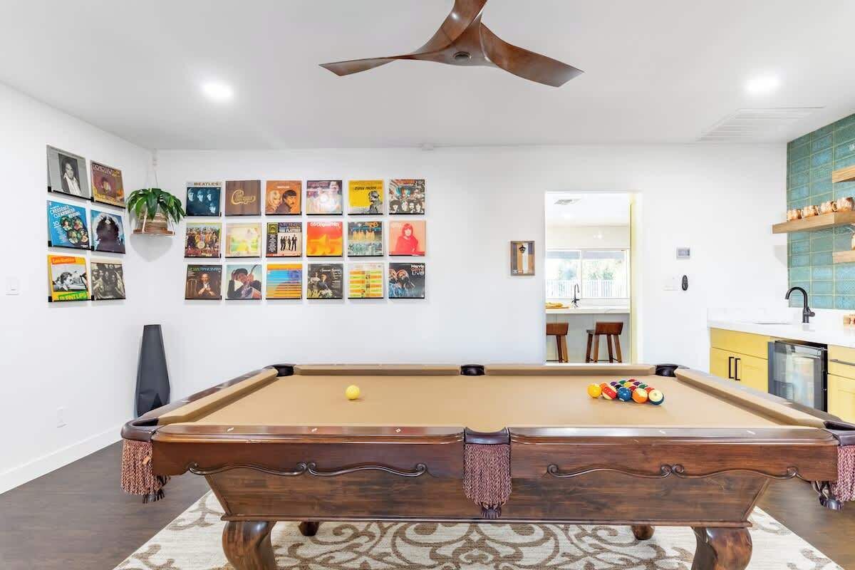 A pool table in a room with a white wall adorned with framed posters.