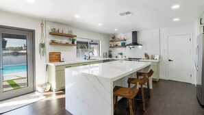 A modern kitchen with a large island, white cabinetry, and a view of a pool.