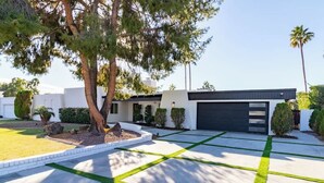 A modern house with a driveway featuring a geometric pattern of grass and concrete.