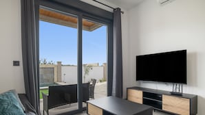 A modern living room with a TV, sofa, and sliding glass doors leading to an outdoor area. - Guest House 'Jazmin' with Private Pool, Wi-Fi and Air Conditioning (Conil de la Frontera)