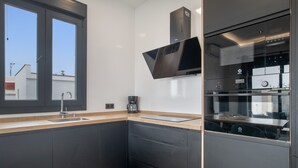 A modern kitchen with dark cabinetry, a stainless steel sink, a coffee maker, and a built-in oven. - Guest House 'Jazmin' with Private Pool, Wi-Fi and Air Conditioning (Conil de la Frontera)
