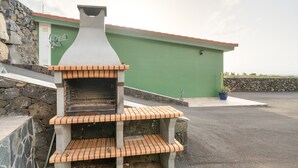A brick-built outdoor oven with a chimney, set against a green building with a stone wall and a door. - Studio 'De Tato' with Mountain View, Private Terrace and Wi-Fi (La Frontera)