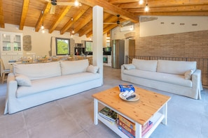A spacious living area with two white sofas, a wooden coffee table, and a kitchen in the background. - Rural House 'La Rossa' with Mountain Views, Private Pool and Wi-Fi (Girona)