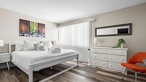 A modern bedroom with a bed, nightstands, a dresser, and a chair.