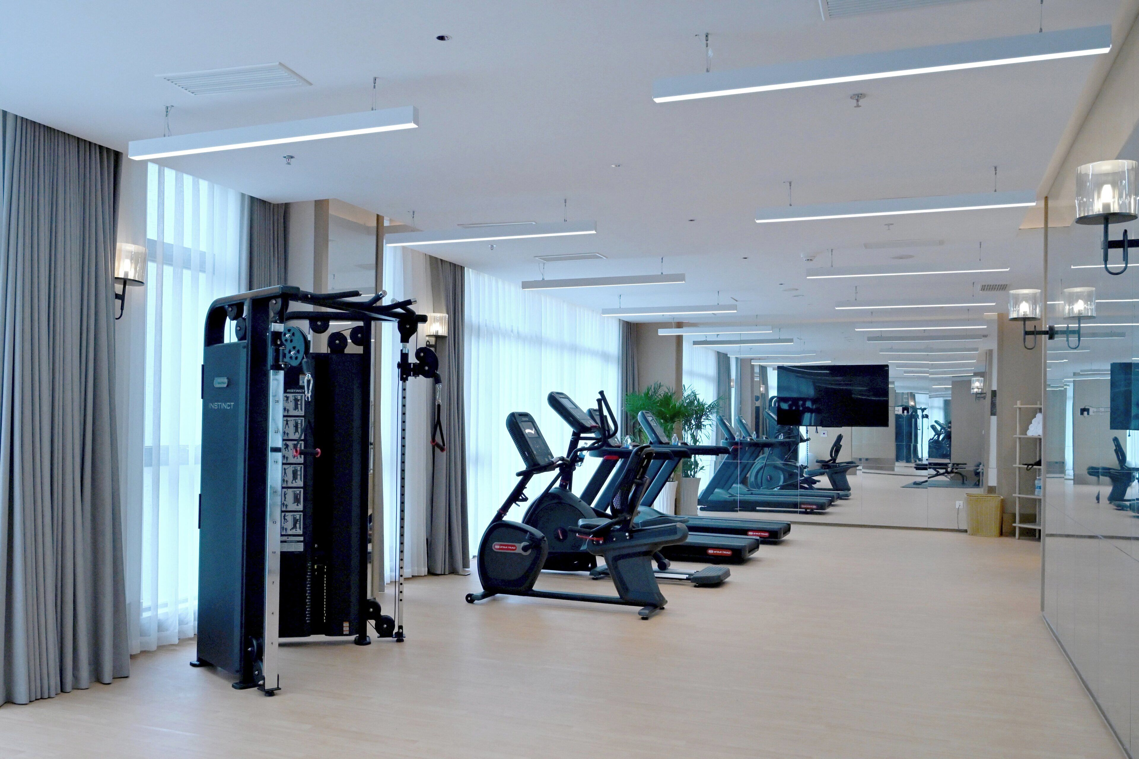 A modern gym with cardio equipment, mirrors, and a clean, spacious layout.