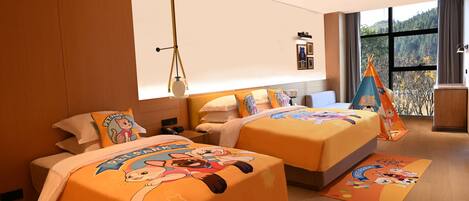 A hotel room with two beds, each with a cartoon-themed bedspread, a window with a view of trees, and a wooden floor.