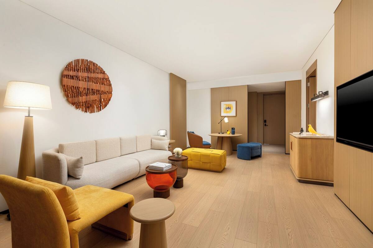Un salon moderne avec un canapé, des fauteuils, une table basse et un téléviseur.