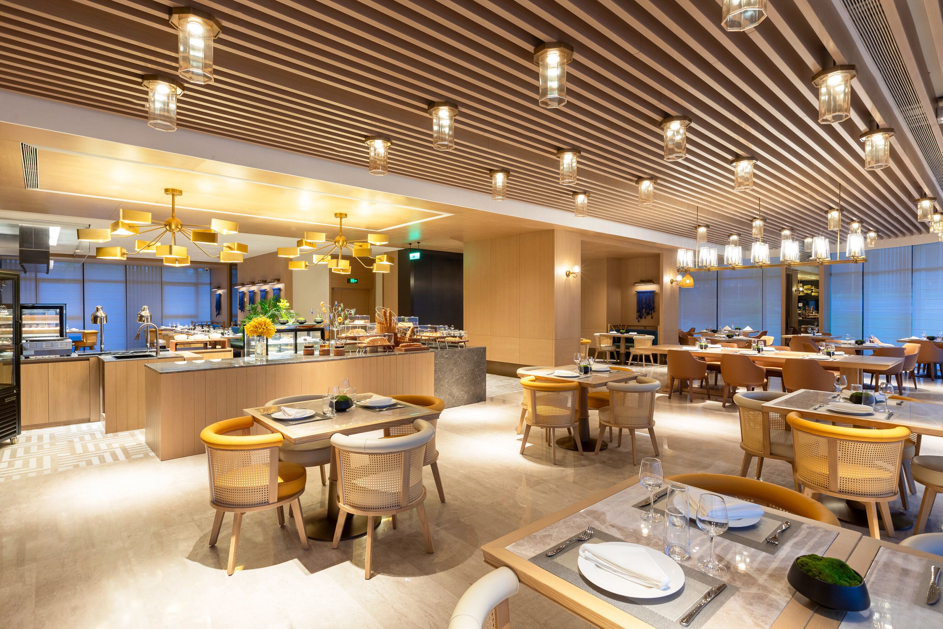 Een modern restaurant met houten plafondpanelen, meerdere eettafels met stoelen en hanglampen.