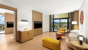 A modern living room with a sofa, ottoman, and a flat-screen TV mounted on a wooden cabinet. - voco Wugong Mountain Jiangxi by IHG (Pingxiang)