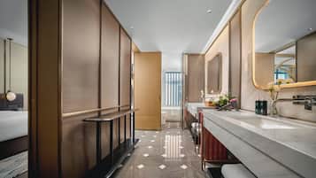 A modern hotel bathroom with a large mirror, a vanity with a marble countertop, and a separate shower area.