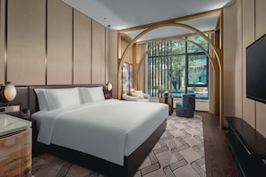 Ein modernes Hotelzimmer mit einem großen Bett, einem Fernseher und Blick ins Freie durch ein großes Fenster.