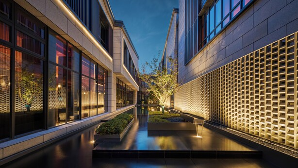 A modern building with a reflective water feature, glass windows, and a geometric wall design. - Hotel Indigo Wuxi Qingming Bridge by IHG (Wuxi)