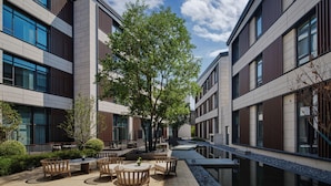 A modern building with a courtyard featuring outdoor seating and a central tree. - Hotel Indigo Wuxi Qingming Bridge by IHG (Wuxi)