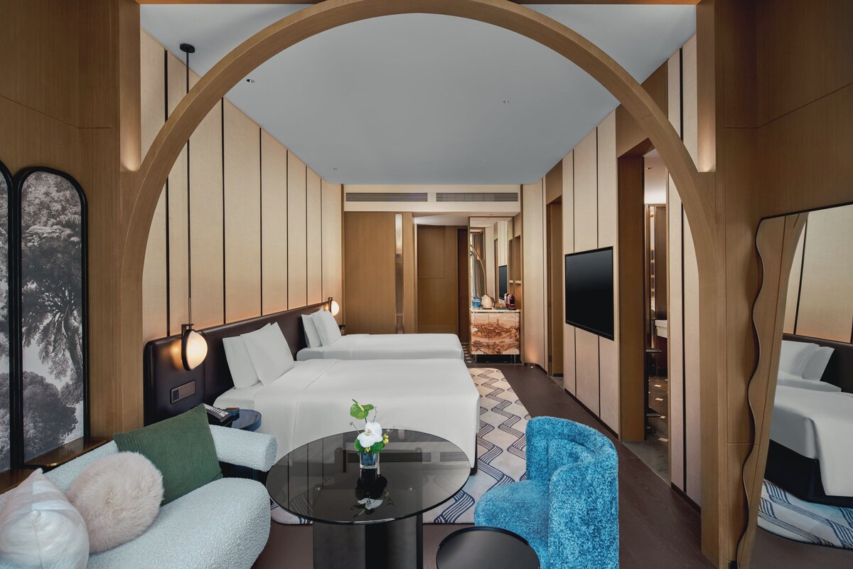 Une chambre d’hôtel avec deux lits, un canapé, une table ronde et un téléviseur.