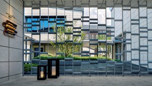 A modern building entrance with a geometric metal fence, a water feature, and a sign on the wall. - Hotel Indigo Wuxi Qingming Bridge by IHG (Wuxi)