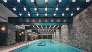 A modern indoor swimming pool with a blue tiled floor, marble walls, and a ceiling with recessed lighting. - Hotel Indigo Wuxi Qingming Bridge by IHG (Wuxi)