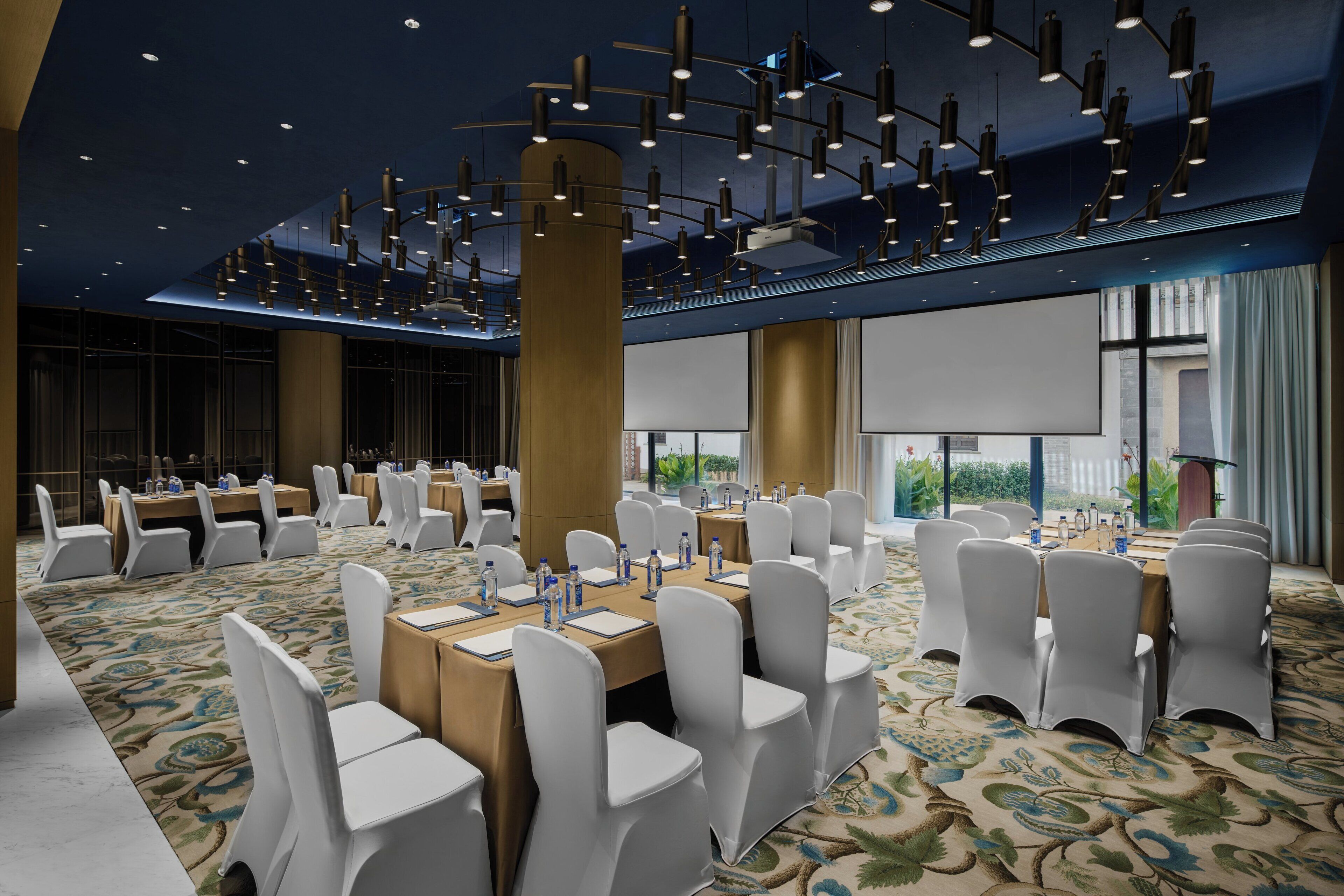 A conference room with round tables, white chairs, and overhead lighting.