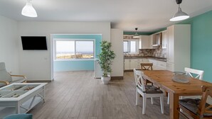 A modern apartment with a dining area, kitchen, and a large window with a view. - Holiday Home 'Elvira' with Sea View, Private Terrace and Wi-Fi (La Frontera)