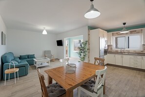 Un espace de vie moderne comprenant une table à manger en bois, un canapé de couleur turquoise et un coin cuisine.