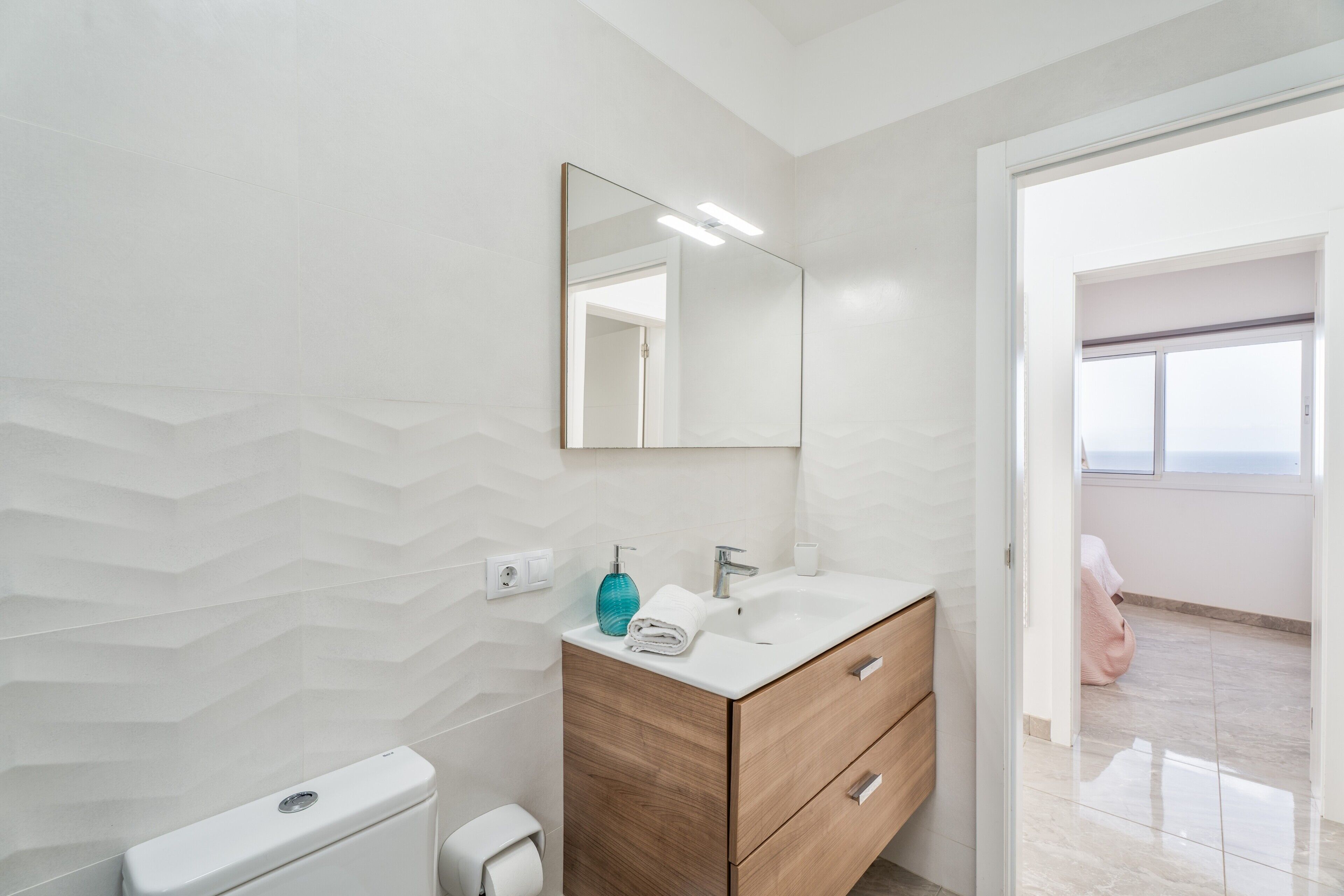 A modern bathroom with a white vanity, a mirror, and a toilet.