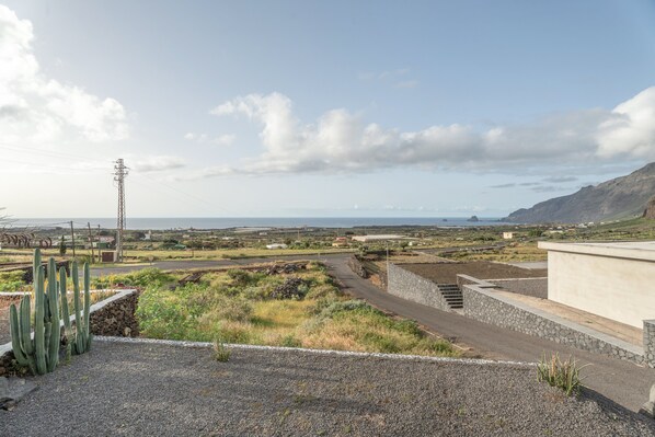 A rural landscape with a road, a tall power line tower, and distant hills.