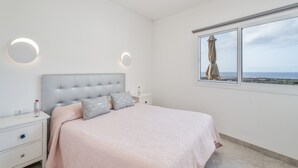 A bedroom with a bed, bedside tables, a window with a view, and wall-mounted lighting. - Holiday Home 'Miramar' with Sea View, Private Terrace and Wi-Fi (Frontera)