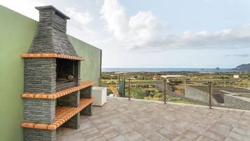 A stone-built outdoor kitchen with a view of a coastal landscape.