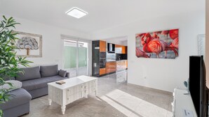 A modern living room with a grey sofa, a white coffee table, and a large painting of flamingos. - Holiday Home 'Miramar' with Sea View, Private Terrace and Wi-Fi (Frontera)