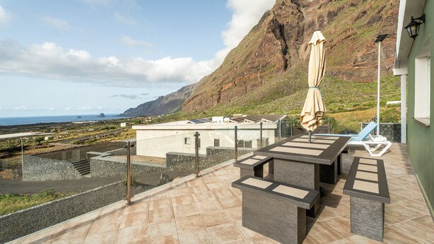 A terrace with outdoor furniture, a view of the sea, and a mountain in the background. - Holiday Home 'Miramar' with Sea View, Private Terrace and Wi-Fi (Frontera)