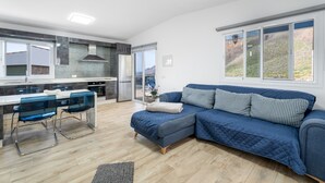 Et moderne køkken med spiseplads, en blå sofa og udsigt til det fri.