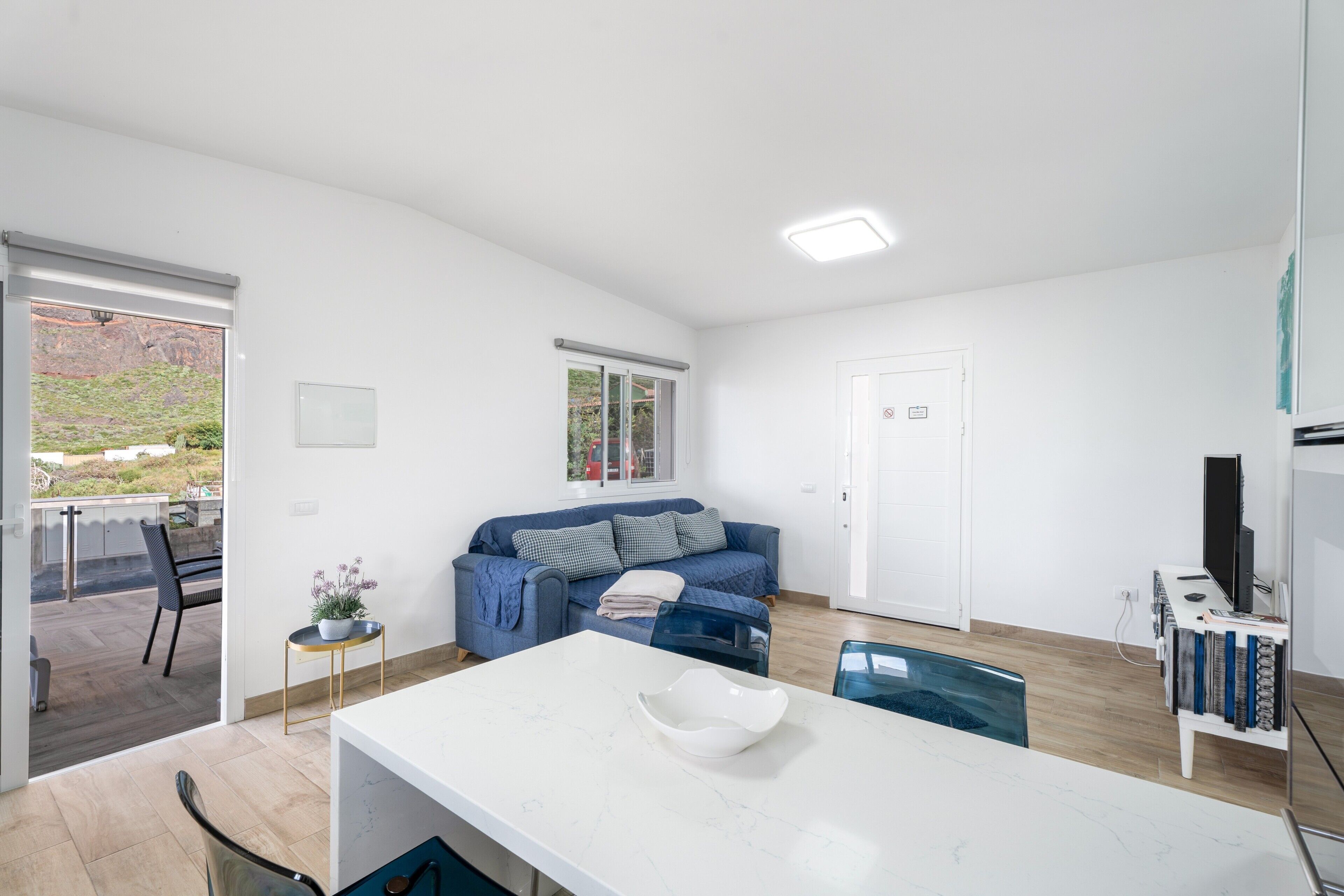 Una sala de estar moderna con un sofá blanco, una mesa de comedor y un mueble para la televisión.