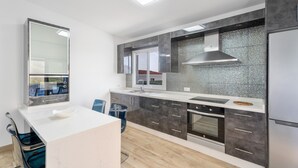 Et moderne køkken med en hvid bordplade, rustfrie stålapparater og et stort vindue.