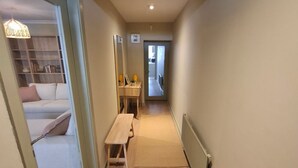 En smal hall med trägolv, ett litet bord och en bänk.