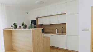 A modern kitchen with white cabinets, a wooden island, and a herringbone floor pattern.