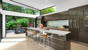 Una cocina moderna con una isla grande, taburetes de bar y vistas a exuberante vegetación.