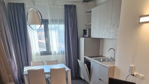 A modern living room with a sofa, a dining table, chairs, a kitchen area with a sink, and a TV. - Water lily wellness 5 stars (Caorle)