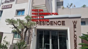 A modern building with a sign indicating free amenities including a spa, swimming pool, gym, and parking. - Water lily wellness 5 stars (Caorle)